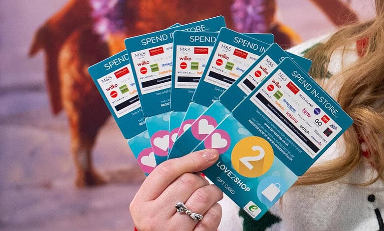 1. Close-up of a person holding Love2Shop gift cards, showcasing multiple cards with various store logos, ideal for gift card giveaways and retail promotions in the UK.