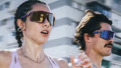 Female and male runners wearing sunglasses during outdoor urban run, showcasing fitness and active lifestyle.