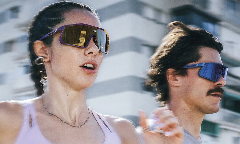 Female and male runners wearing sunglasses during outdoor urban run, showcasing fitness and active lifestyle.