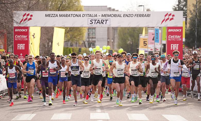 Marathon runners at the starting line of the Mezza Maratona d’Italia, Enzo Ferrari Memorial, ready to begin the race. The image captures a diverse group of athletes in motion, emphasizing endurance an.