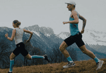 An image of a man and a girl running outdoors on a trail with mountain scenery in the background, highlighting trail running and outdoor fitness.