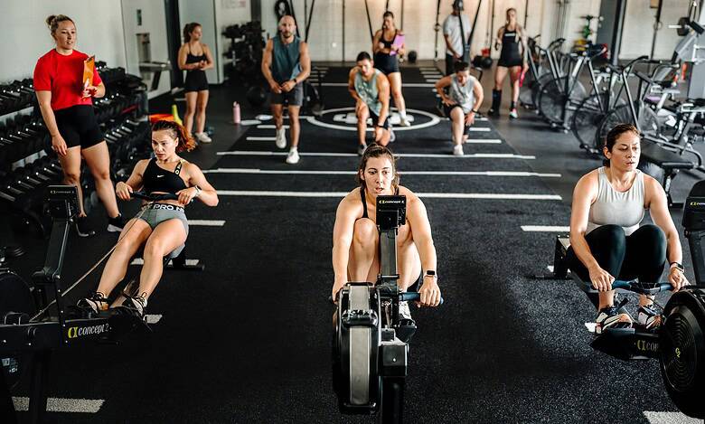 Indoor rowing athletes using data-driven testing methods at a modern gym.