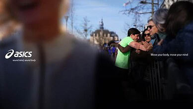 Group of runners and spectators at a running event, with ASICS branding and a motivational slogan, capturing the energy and community spirit of running.