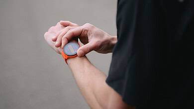 Running Insights - Male runner checking GPS watch outdoors for running metrics.