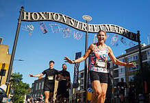 Female runner celebrating crossing the finish line at Hoxton Street Market during Saucony Run Shoreditch Half 2026 event.