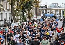 Large group of runners participating in the Stockport 10K race, with an archway and cityscape in the background.