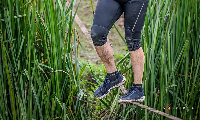 Participant crossing a water obstacle during Wolf Run's 15th anniversary event, showcasing endurance and determination.
