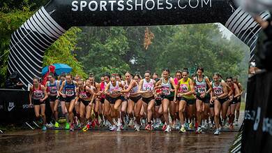 Start of the UK Athletics 5K road race in Cardiff with runners under a SPORTSSHOES.COM arch.