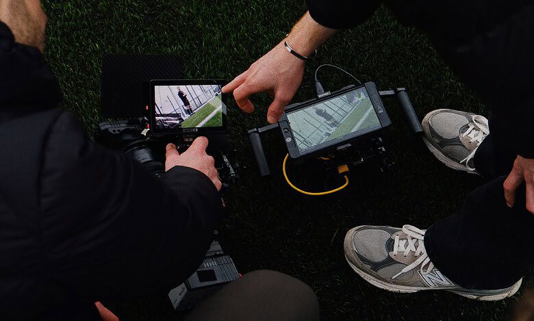 Two runners reviewing running data on a smartphone and GPS device during a training session.