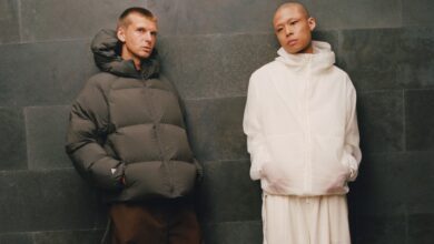 Two models wearing winter outerwear from adidas and Arte Antwerp's FW26 collection, standing against a dark wall.