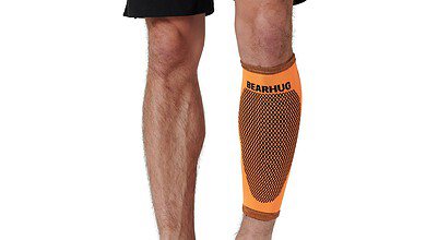 Orange Bearhug compression sleeve on a man's lower leg, knee to ankle, showing a dotted pattern and branding.