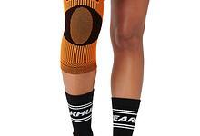 Athlete wearing an orange knee sleeve labeled Bearhug on a kneeling leg with black compression socks.