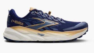Brooks Cascadia trail running shoes in navy blue with beige and gold accents, designed for outdoor trail running and stability.