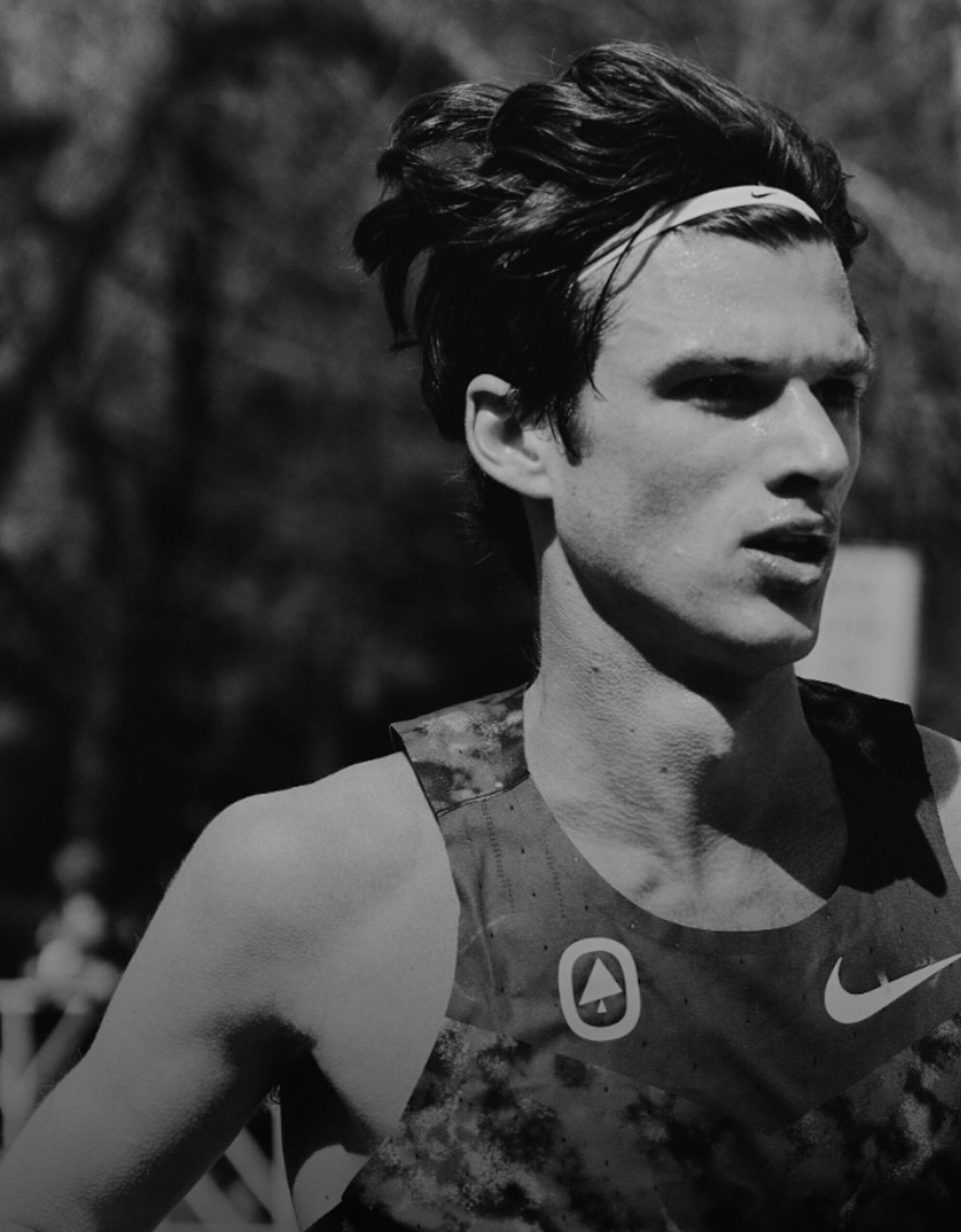 Black-and-white photograph of Charles Hicks running in a vest and headband