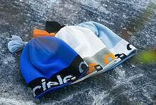 Blue, white, and grey beanie with orange accents on a rocky surface, featuring the Running Insights branding along the cuff.