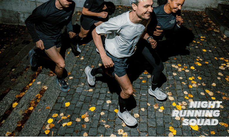 Group of four runners training together at night on a cobblestone street, wearing athletic gear, with fallen leaves around, promoting night running fitness.