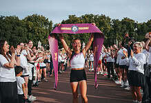 Esmée Gummer holds a Guinness World Records finish ribbon above her head as supporters applaud