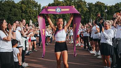 Esmée Gummer holds a Guinness World Records finish ribbon above her head as supporters applaud