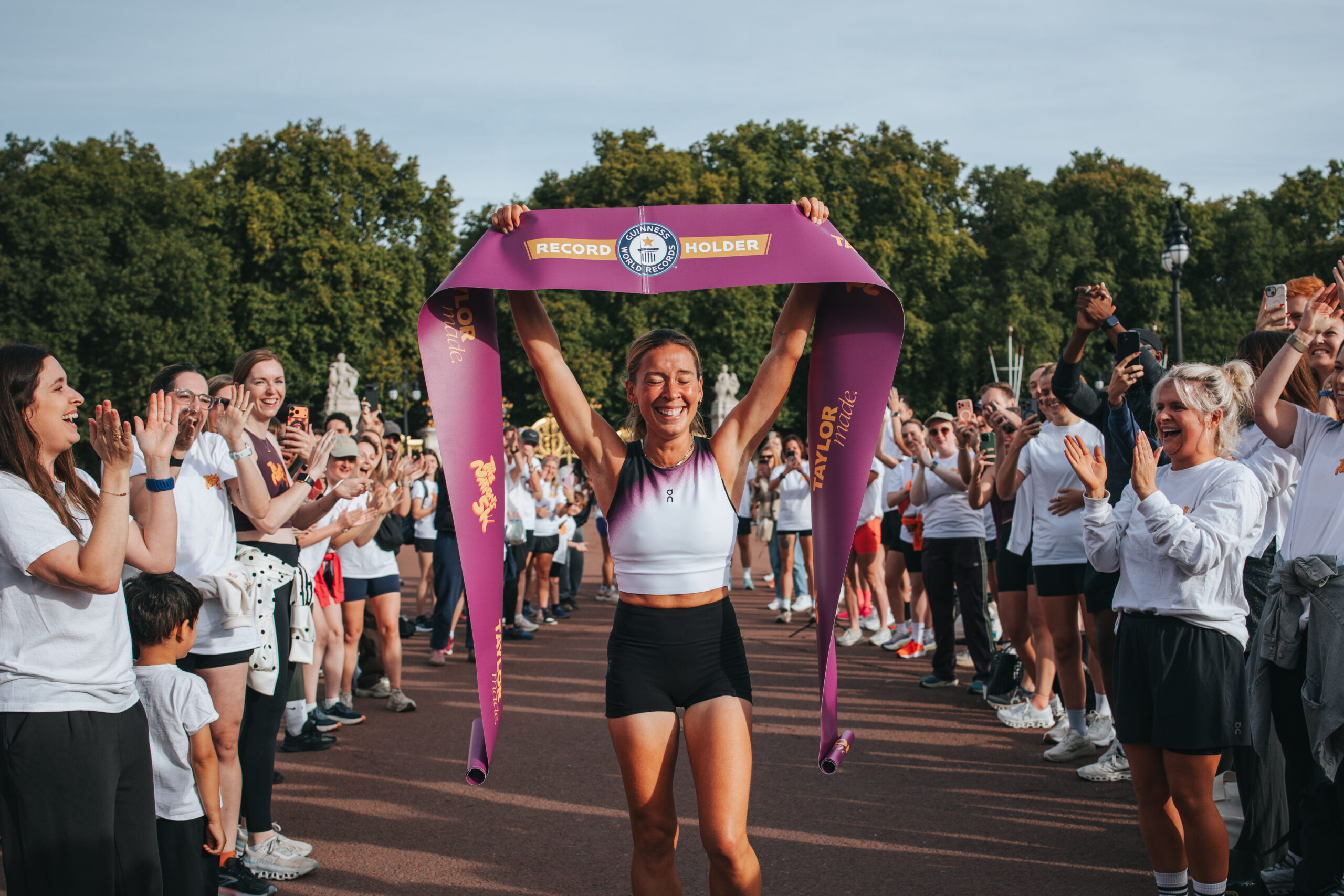 Esmée Gummer holds a Guinness World Records finish ribbon above her head as supporters applaud