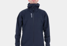 Man wearing INOV8 VentureShell waterproof jacket with hood, designed for wet-weather outdoor activities.