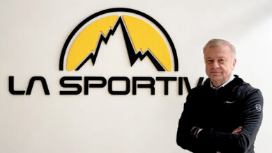 Man standing confidently with arms crossed in front of La Sportiva logo, showcasing outdoor sports and running gear expertise.