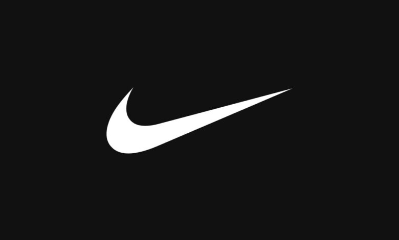 Close-up of Nike swoosh logo on black background, symbolising running and athletic performance.