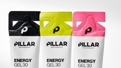 Three Pillar Performance Energy Gel packets in black, yellow, and pink with a white background, showcasing their vibrant packaging design.