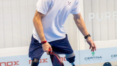 Male athlete with prosthetic legs practicing adaptive sports on a blue indoor court, demonstrating resilience and determination.