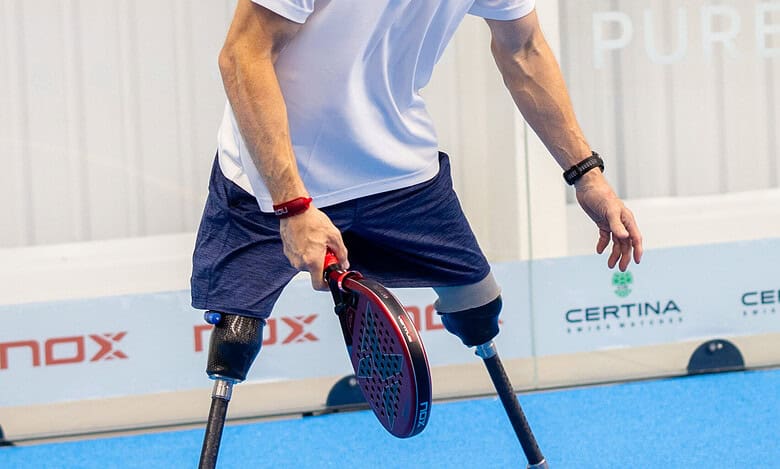 Male athlete with prosthetic legs practicing adaptive sports on a blue indoor court, demonstrating resilience and determination.