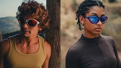 Two runners wearing sunglasses outdoors, one male with curly hair and a yellow tank top, and one female with braided hair and a black athletic top, preparing for a run.
