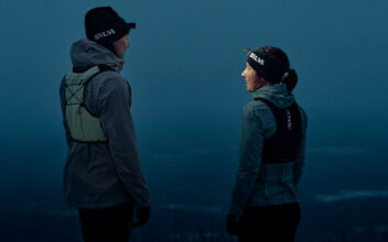 Two runners in trail running gear talking outdoors during dusk, highlighting outdoor running and fitness.