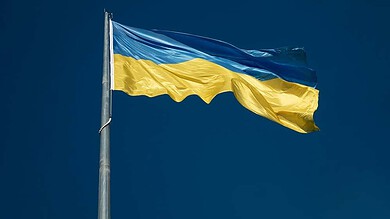Ukrainian flag waving on a tall flagpole against a clear blue sky, symbolizing national pride and resilience.