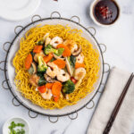 Mi Xao Gion (Pan fried noodles) with shrimp, scallops, and vegetables on a plate.