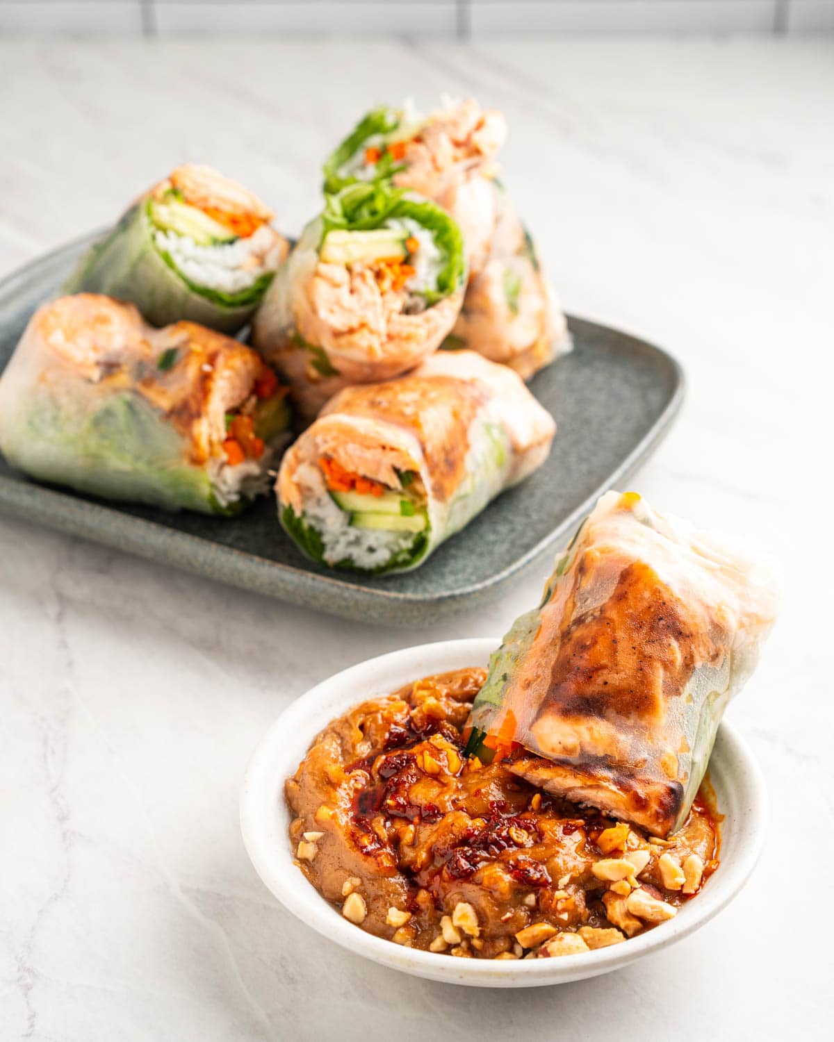 salmon spring roll dipping into peanut sauce.