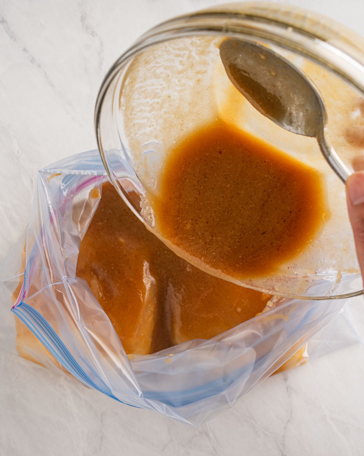 pouring miso sauce over cod into ziplock bag.