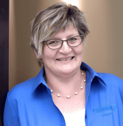 Frau mit Brille und blauer Arbeitsjacke bei Schweizer Fahrräder Breisach.