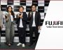 Group of four people holding Fujifilm cameras at event.