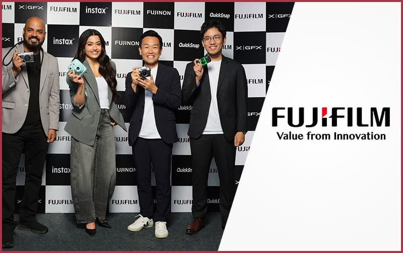 Group of four people holding Fujifilm cameras at event.