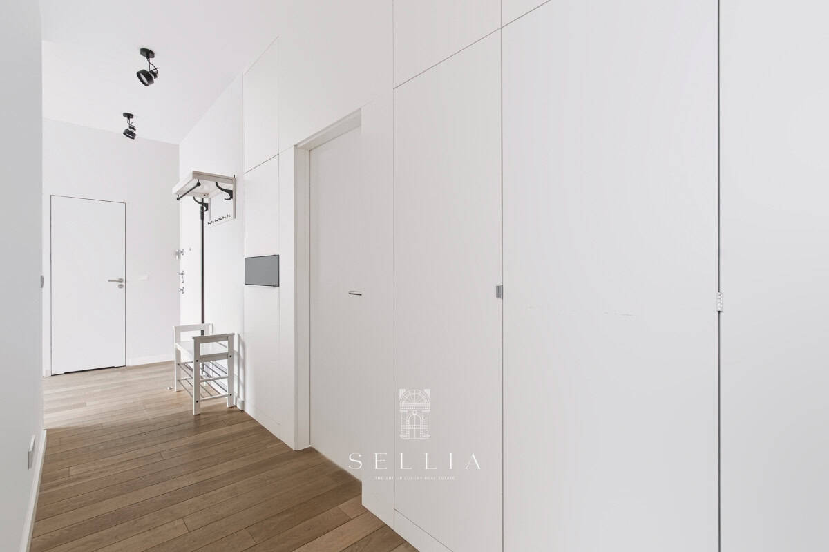 Nowoczesny, jasny apartament z białymi ścianami i drewnianą podłogą.