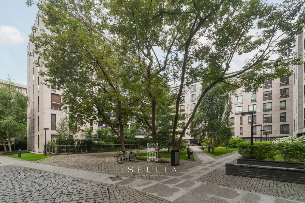 Zielony park z drzewami i ścieżkami w Sellia Estate, Warszawa.