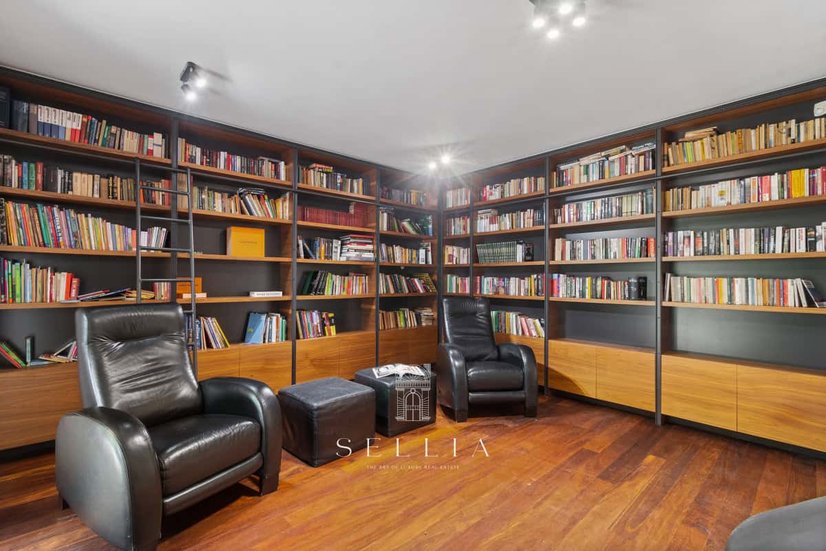 Biblioteka z regałami pełnymi książek i dwoma wygodnymi fotelami.