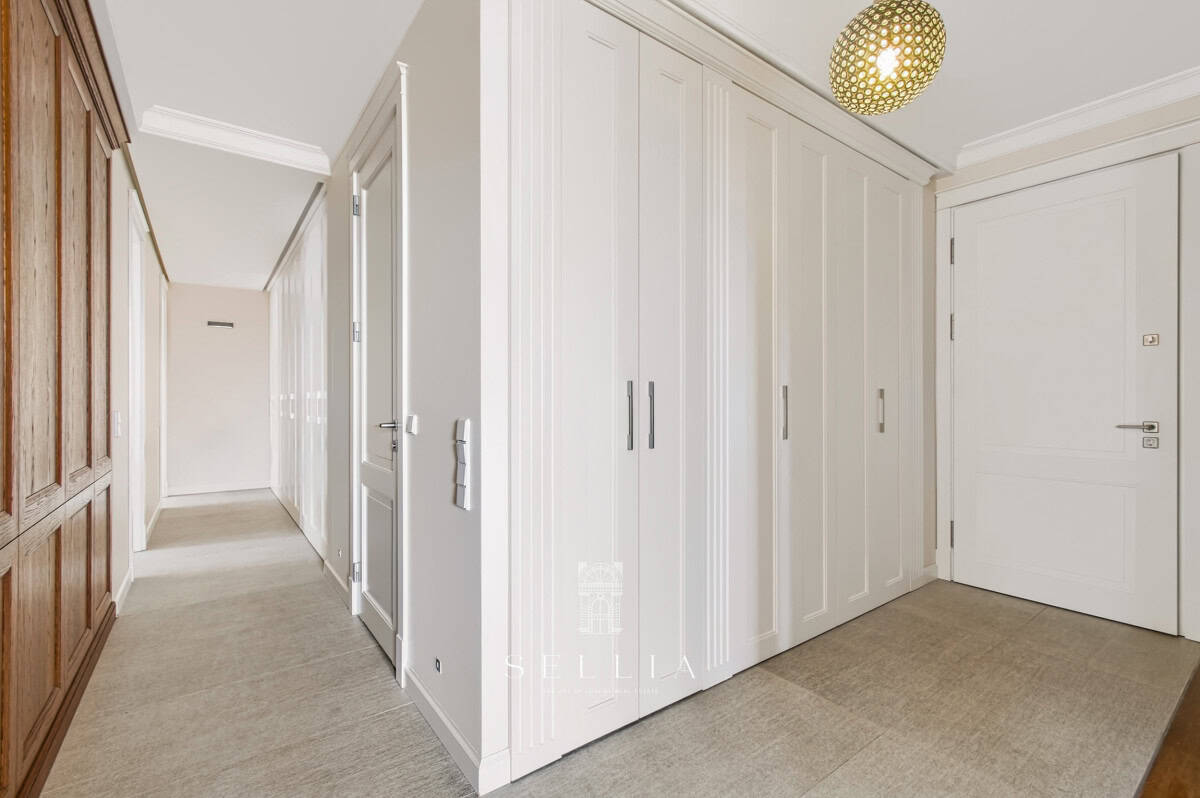 Przedpokój z białymi szafami i drzwiami w apartamencie na Żoliborzu.
