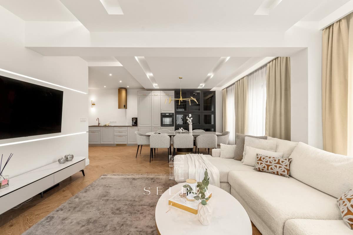 Przestronny, nowoczesny salon z dużymi oknami i eleganckim wystrojem.