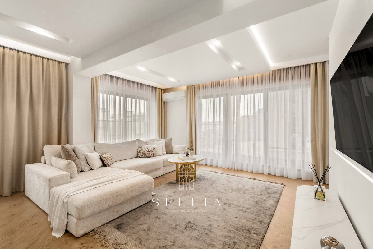 Przestronny, jasny salon z dużymi oknami i eleganckim wystrojem.