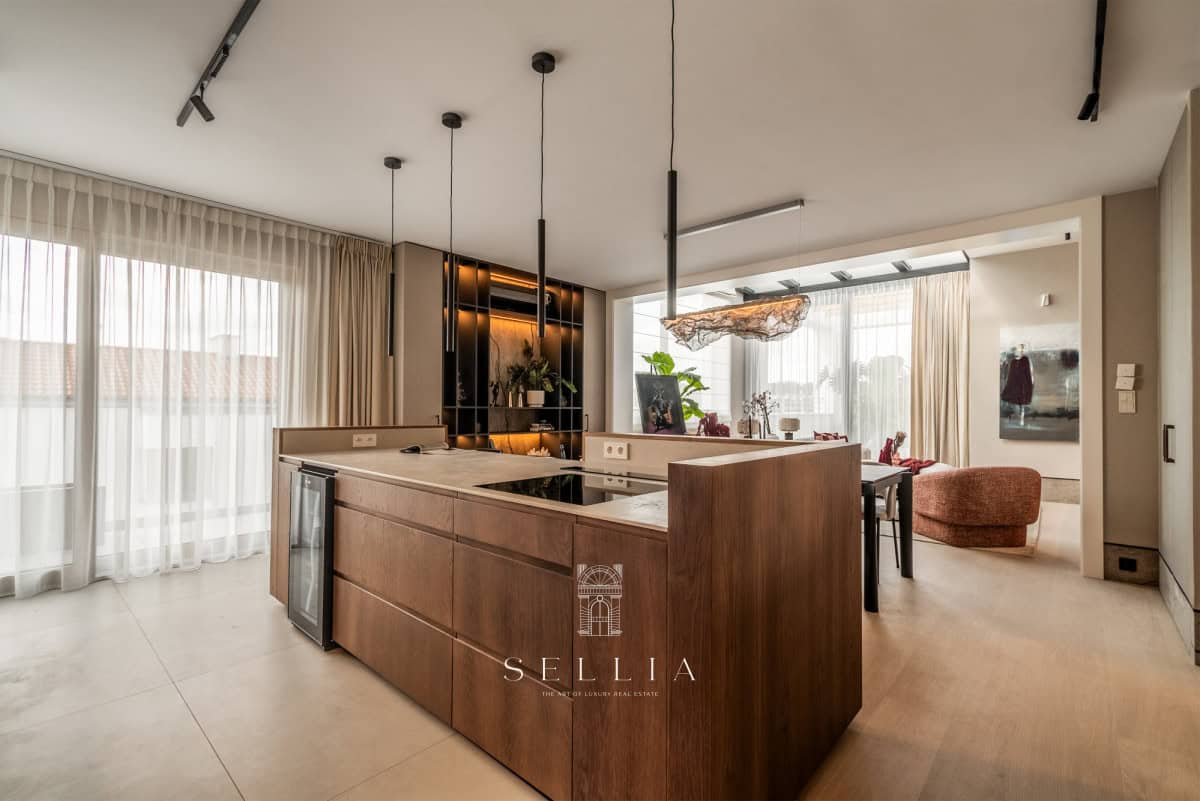 Przestronna kuchnia z wyspą i dużymi oknami w penthousie.