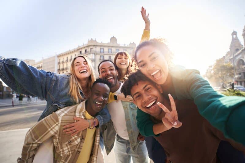 Vibrant group of diverse friends taking a selfie in downtown near Flying Pig Hostel.