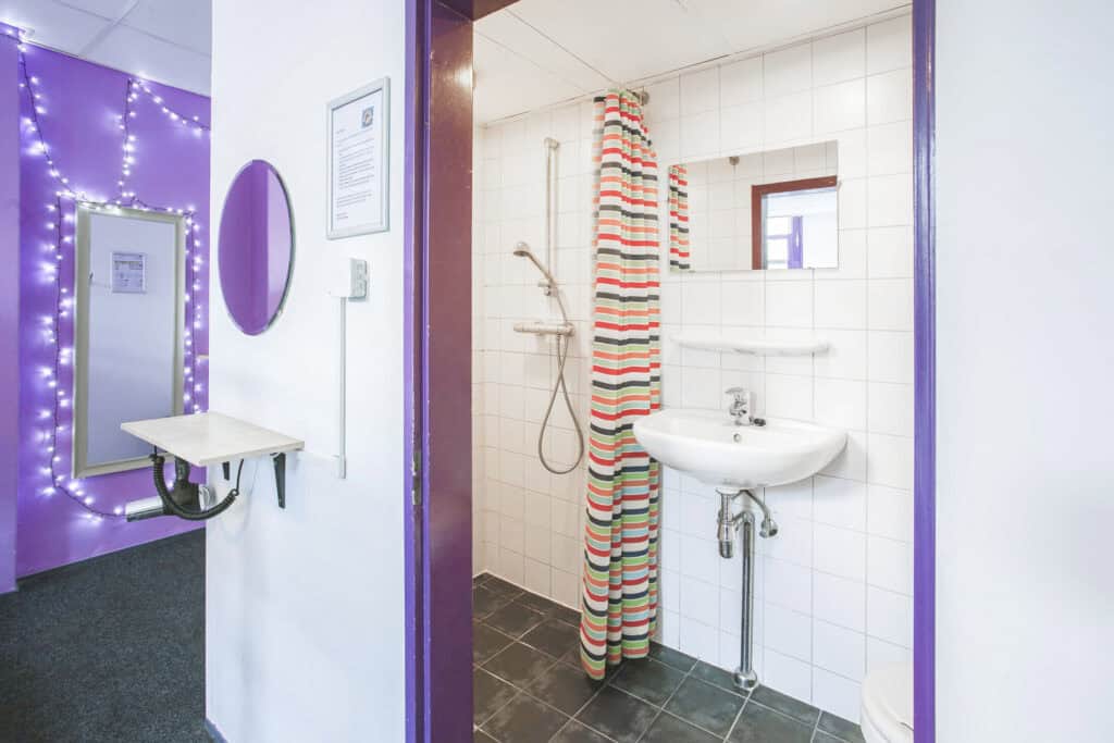Small hostel bathroom with shower and sink at Flying Pig Downtown, vibrant and clean.