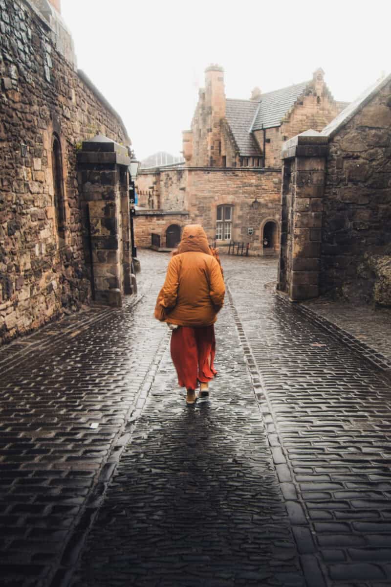 A person walking through a castle entrance on a rainy day in a hostel setting.