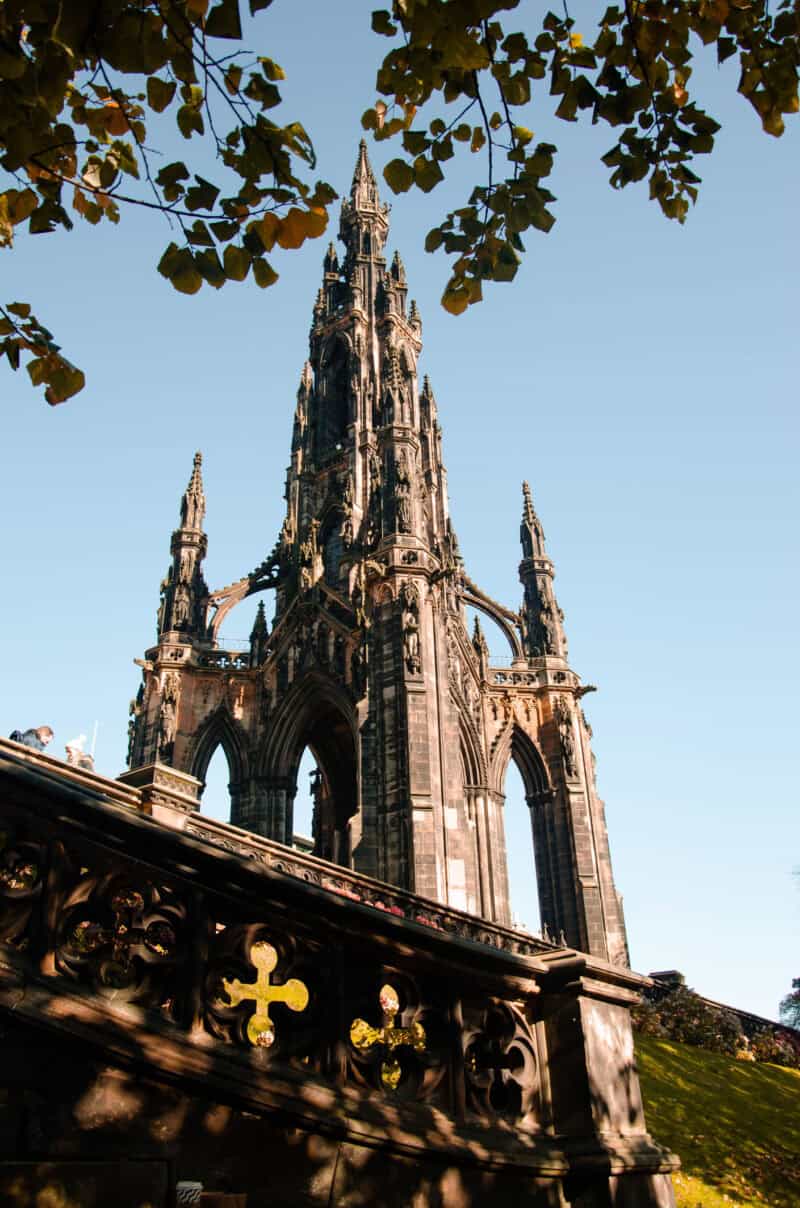 View of the Edinburgh Castle spire with stone wall and leaves in the foreground. at St Christopher's Edinburgh Old Town hostel