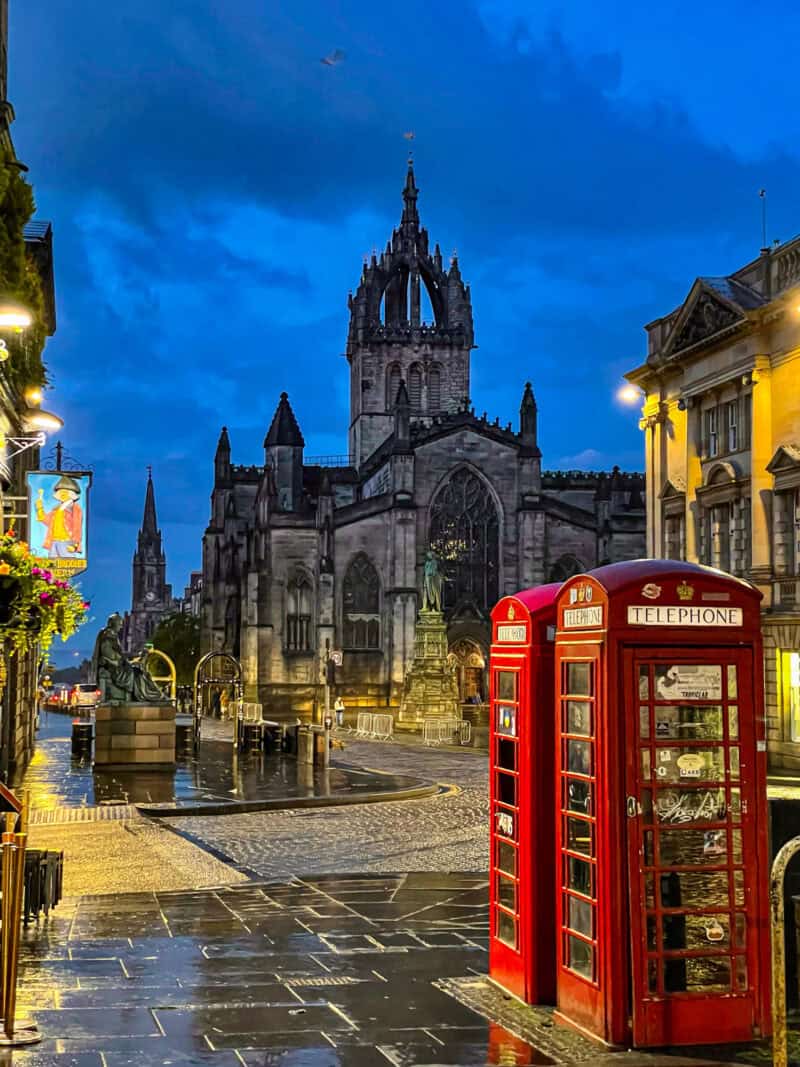 Cobbled street with historic church and red telephone box in the foreground. at St Christopher's Edinburgh Old Town hostel